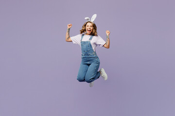 Full body overjoyed young woman wearing casual clothes bunny rabbit ears jump high do winner gesture isolated on plain pastel light purple background studio portrait. Lifestyle Happy Easter concept.