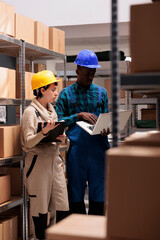 Warehouse workers searching customer order information on laptop and monitoring parcels audit. African american and caucasian storehouse managers holding clipboard and computer managing inventory