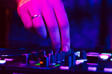 Hands of a DJ creating and regulating music on dj console mixer at club concert