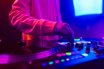 Hands of a DJ creating and regulating music on dj console mixer at club concert