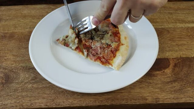 gros plan sur une personne mangeant une part de pizza dans une assiette