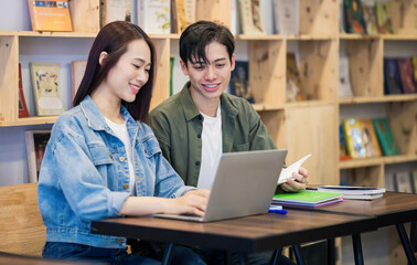 Naklejka na ściany i meble Young Asian couple studying at library