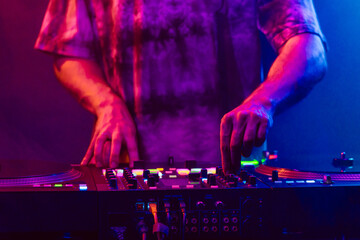 Hands of a DJ creating and regulating music on dj console mixer at club concert