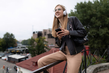 Fototapeta na wymiar woman young journalist listening to music in headphones on the street