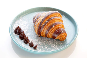 Brioche chocolate croissant served on a blue plate.