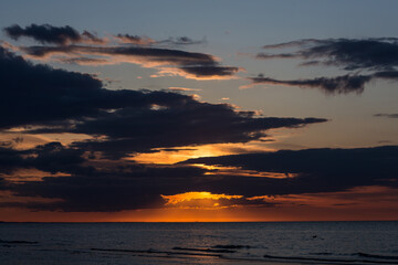 Sun hiding behind the clouds over sea in sunset