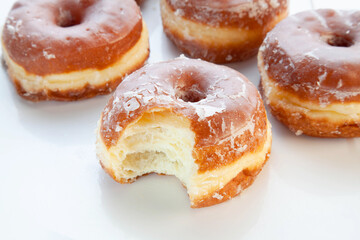 Bite taken out from a brioche glazed doughnut.