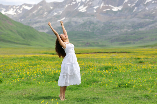 Excited woman in white dress raising arms