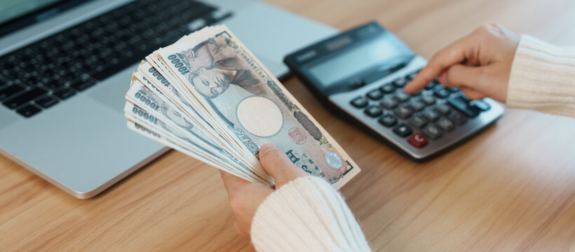 Woman hand counting Japanese Yen banknote with calculator. Thousand Yen money. Japan cash, Tax, Recession Economy, Inflation, Investment, finance, salary and payment concepts