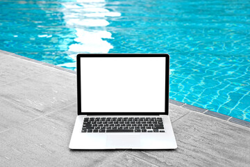 Laptop with blank screen for creative design on floor near swimming pool edge background. Computer notebook with monitor clipping path for present landing page design. Laptop computer mock up template