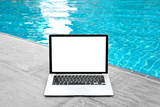 Laptop with blank screen for creative design on floor near swimming pool edge background. Computer notebook with monitor clipping path for present landing page design. Laptop computer mock up template