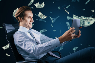 Digital business, success, money, freedom and power concept with happy businessman on office chair using digital tablet on dark background under dollar banknotes rain - obrazy, fototapety, plakaty