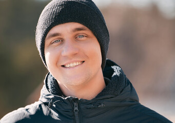 Male portrait in winter. The man wears a black hat and a black winter jacket.