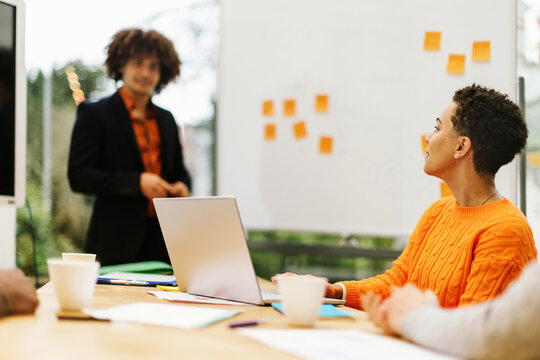 young Brazilian woman in casual clothing listens with interest to the lecture or workshop in the classroom with her laptop