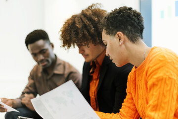 Three multiracial young adults sit, discuss, and study the project together