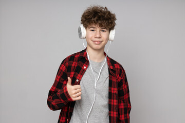 Obraz premium Attractive boy, teenager in headphones on gray background