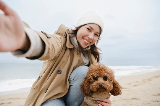 Happy woman taking selfie with dog at beach