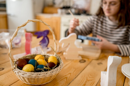 Colorful easter eggs in wicker basket on table at home