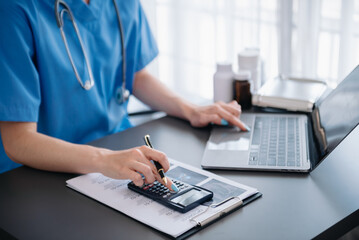 Healthcare costs and fees concept.Hand of smart doctor used a calculator and smartphone, tablet for...