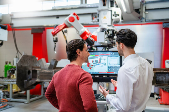 Engineers discussing with each other at robot factory