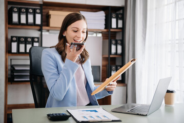 Confident woman with a smile standing holding notepad and tablet at the modern office...