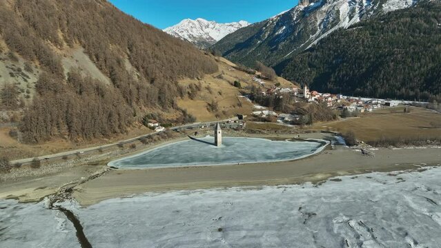 Drone dolley shot of the sunken church of Graun on a frozen lake in Italy.
