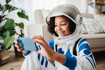 Girl wearing space suit using smart phone sitting at home