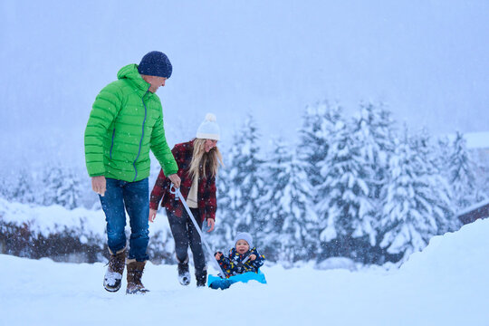 Mother and father with son sitting on sled in snow