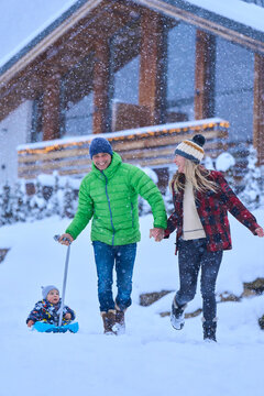 Happy father and mother with son sitting on sled in snow