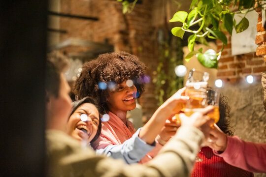 Happy friends toasting beer glasses celebrating at restaurant