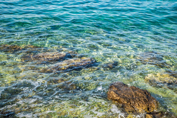 rocky sea shore with transparent blue water.