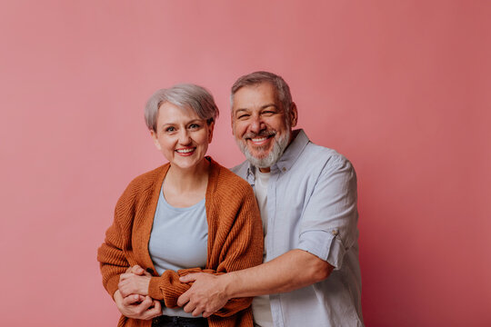 Mature man and woman against pink background