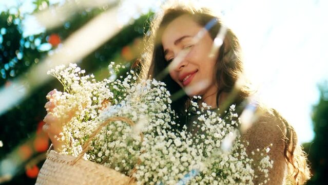 Beautiful happy woman holds a bunch of small white flowers in her hands