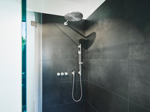 Shower Amidst Black Tile Wall In Bathroom Of Modern Apartment