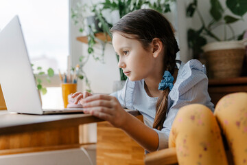 Girl using laptop sitting at table in home
