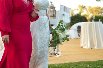 Detail of the bride's bouquet on the arm of her godmother before the wedding ceremony. Wedding...