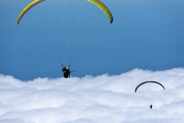 Flight above the clouds, paragliders  are flying on a paraglider in the sky. Tandem flight above the clouds