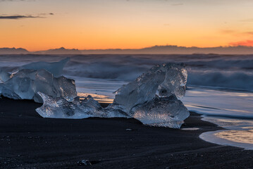 Ice blocks on diamond beach at the south coast of Iceland during sunrise with beautiful orange colors.
