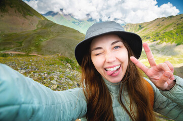Self-portrait of a young cheerful beautiful caucasian girl with a backpack in the wild in the...
