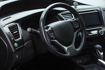 Modern business car interior with dashboard panel and steering wheel. Driver seat view.