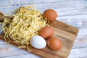 Raw yellow italian pasta tagliatelle with eggs on wooden background