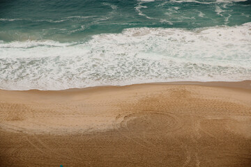 Fototapeta na wymiar Aerial view of Ipanema Beach, Brazil, with golden sand, turquoise sea and white foam on a cloudy day without people.