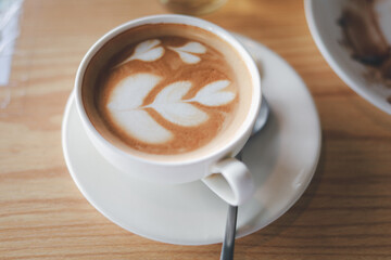 Hot cappuccino, vintage style coffee powder and coffee beans with green leaves On a black background
