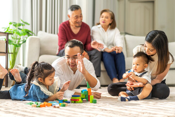 Portrait of enjoy happy love asian big family father and mother with little asian girl smiling activity learn and skill brain training play with toy build wooden blocks board education game at home