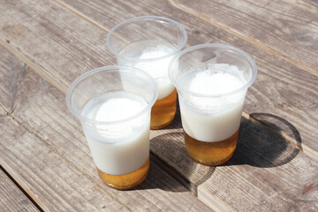 Three plastic cups of light beer standing on wooden boards