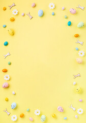 Easter Eggs with Sweets and Spring Flowers on Yellow Background