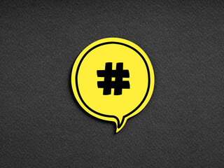 Hashtag symbol on yellow speech bubble on black background. Social media network marketing communication concept.