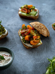 Sandwiches with avocado, cucumber, cherry and cottage cheese in whole grain bread. A healthy snack. Creamy dips. Restaurant serving of sandwiches.