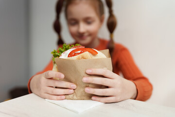 Little girl going to eat pita souvlaki in Greek restauant. White elementary age kid holding big...