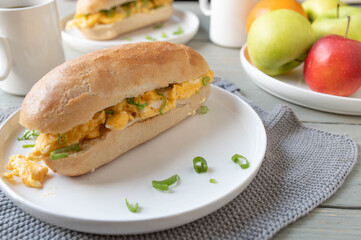 Breakfast baguette bun with scrambled egg and chives on kitchen table
